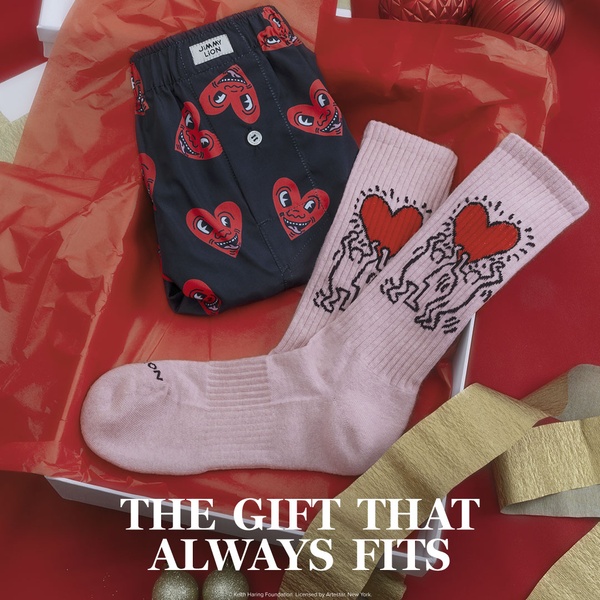 A high-angle flat lay shot showcasing patterned boxer shorts and matching socks inside a gift box on red tissue paper.